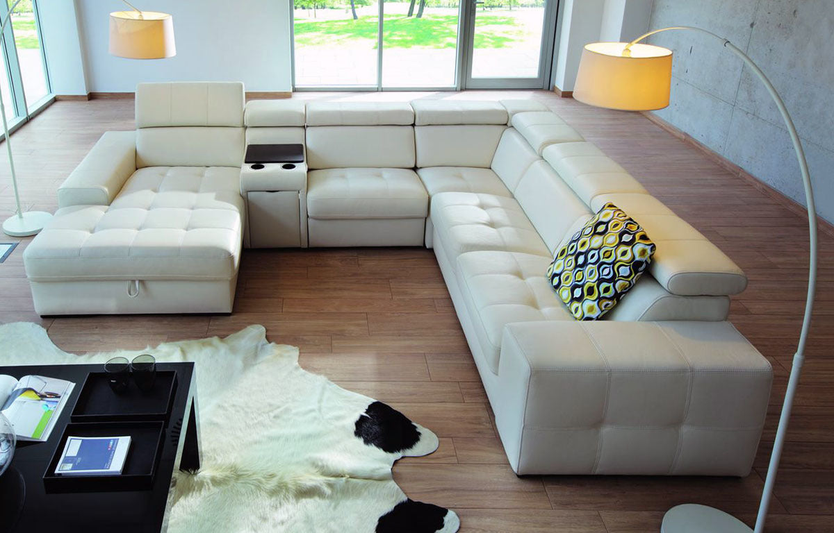 Nagy bézs bőr kanapé tűzött ülőfelülettel.