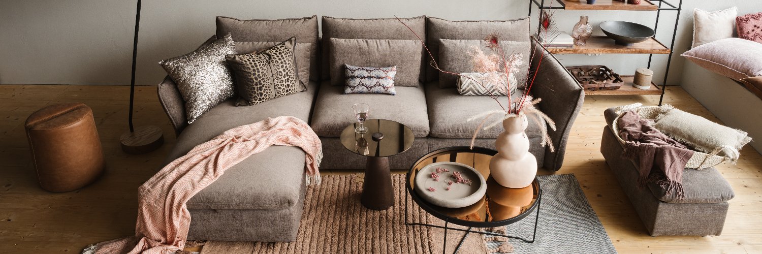 Háromszemélyes barna szövet sarokkanapé puffal.